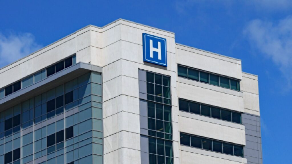 A hospital with a blue 'H' sign on it