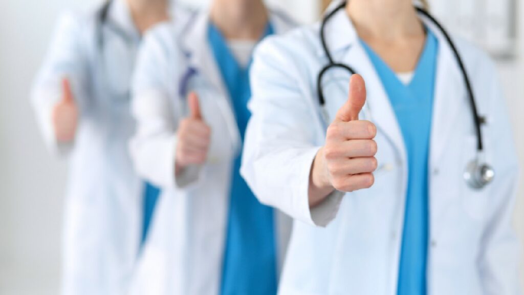 Three doctors standing in a line giving a thumbs up towards the camera