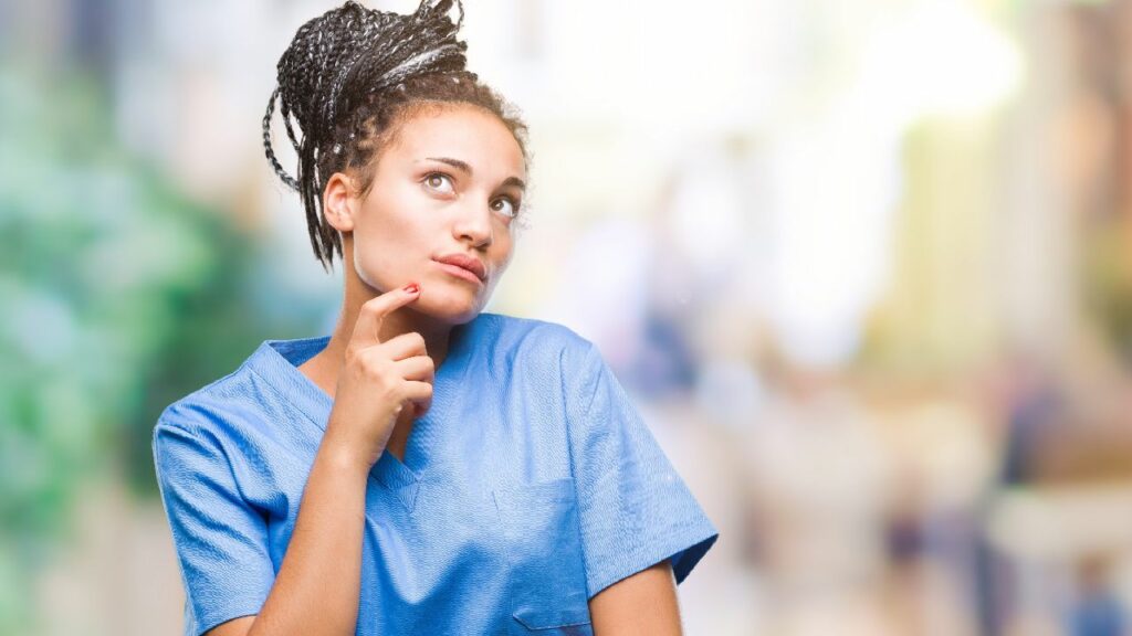 A female nurse with her finger on her chin, looking like she is deep in thought